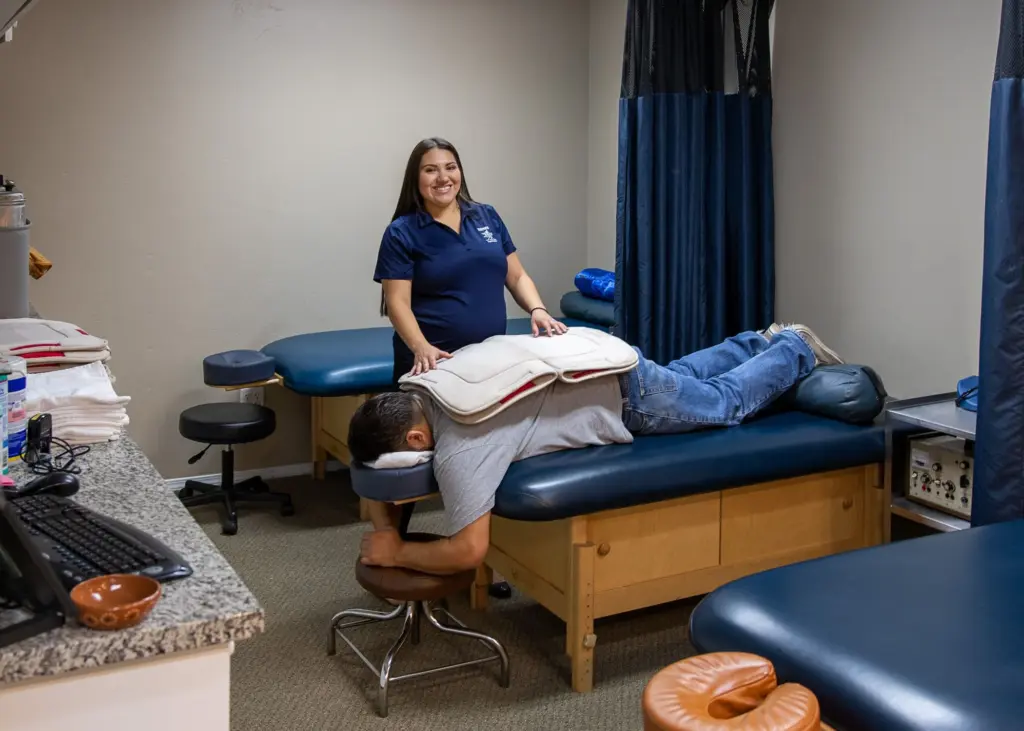 A patient relaxing face-down on a massage table with a therapist