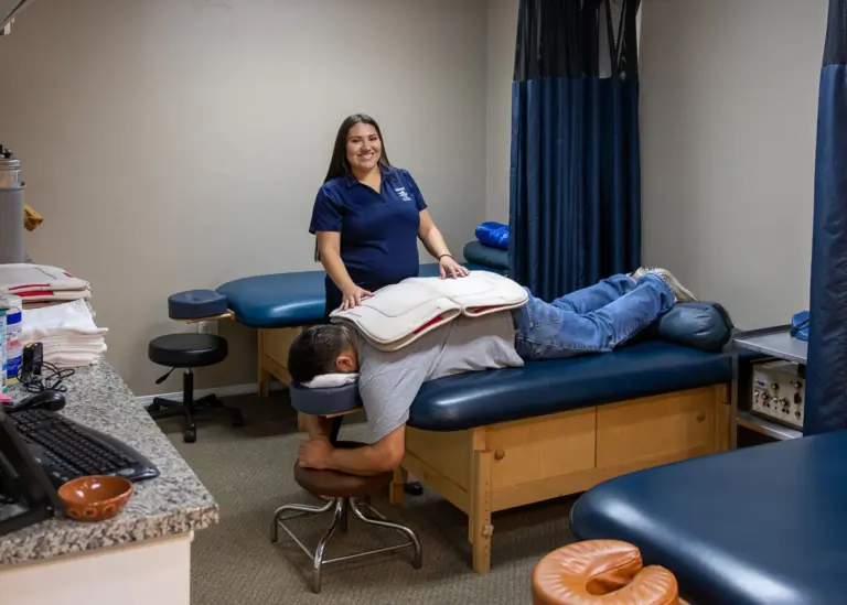 A patient relaxing face-down on a massage table with a therapist